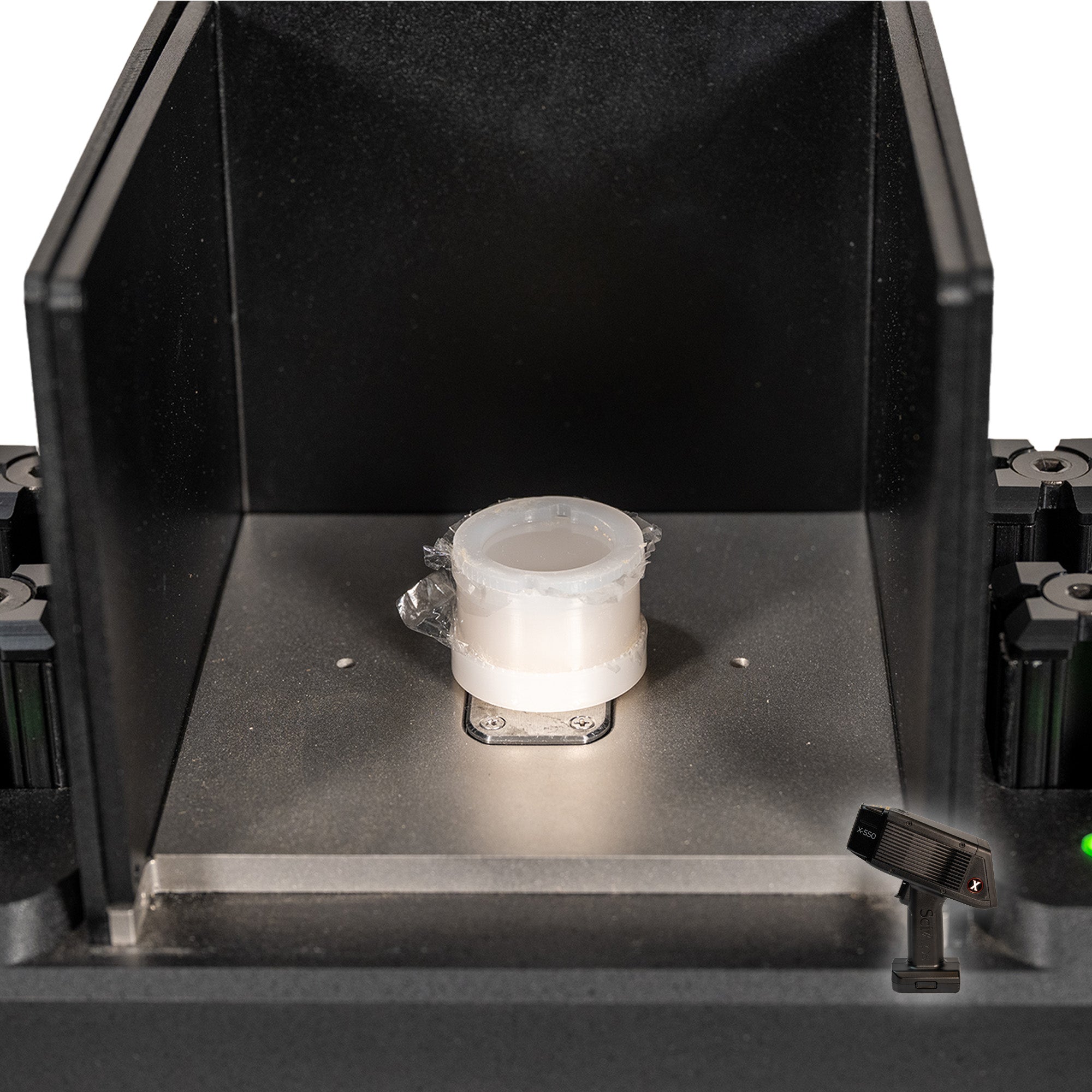 The SciAps X-550 Handheld XRF Benchtop Test Stand showing the sample chamber and a sample cup